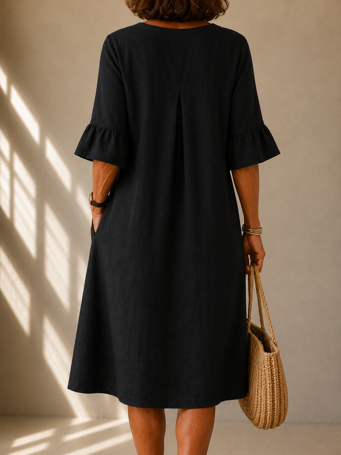 Isabelle buttoned flowy dress in black, back view with box pleat