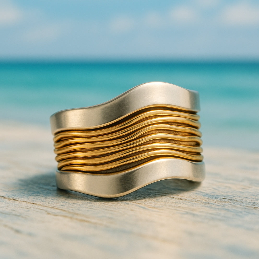 Wide silver ring with gold wire detail photographed by the sea