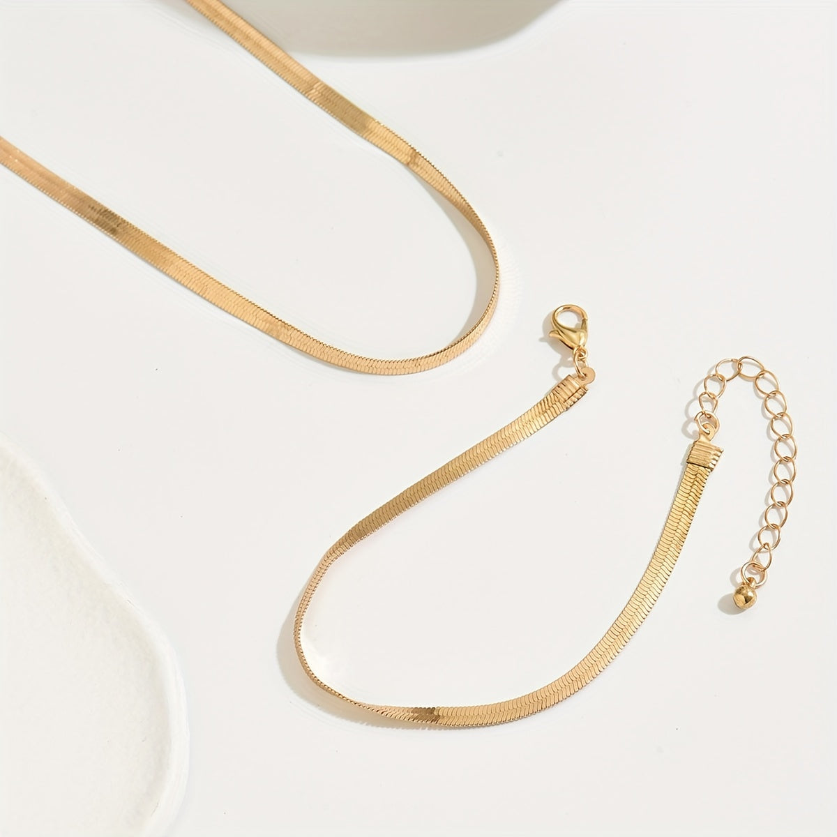 Gold flat chain necklace and bracelet with clasp and extender chain, flat lay