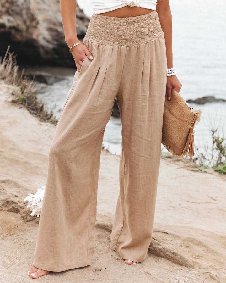 Annelise smocked waist trousers in beige, full-length front view with hand in pocket