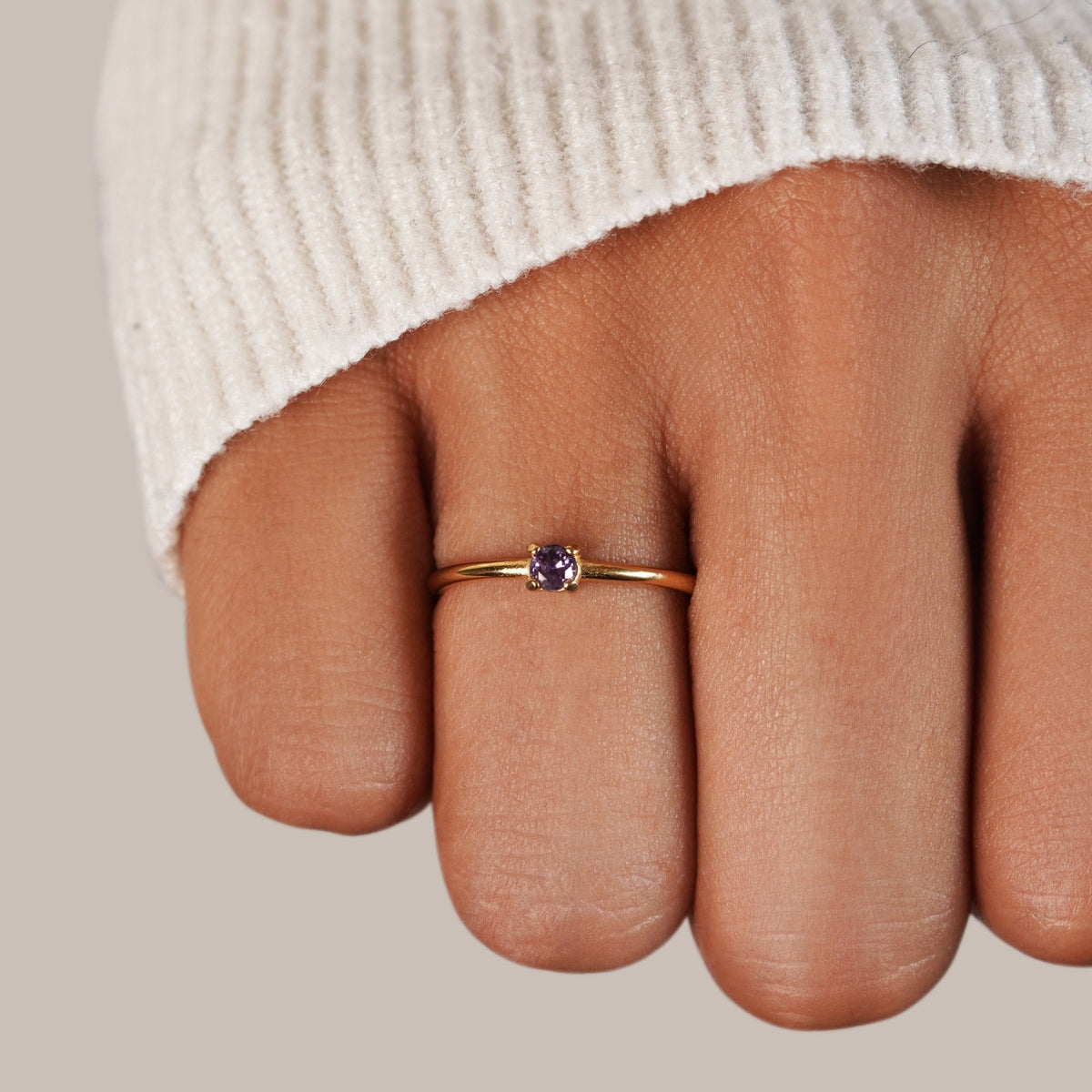 Gold birthstone ring with purple amethyst stone worn on the hand
