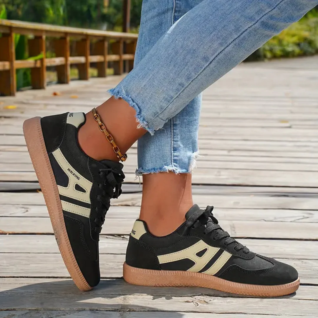 Ceridwen lace-up trainers in black with cream stripes, worn with jeans