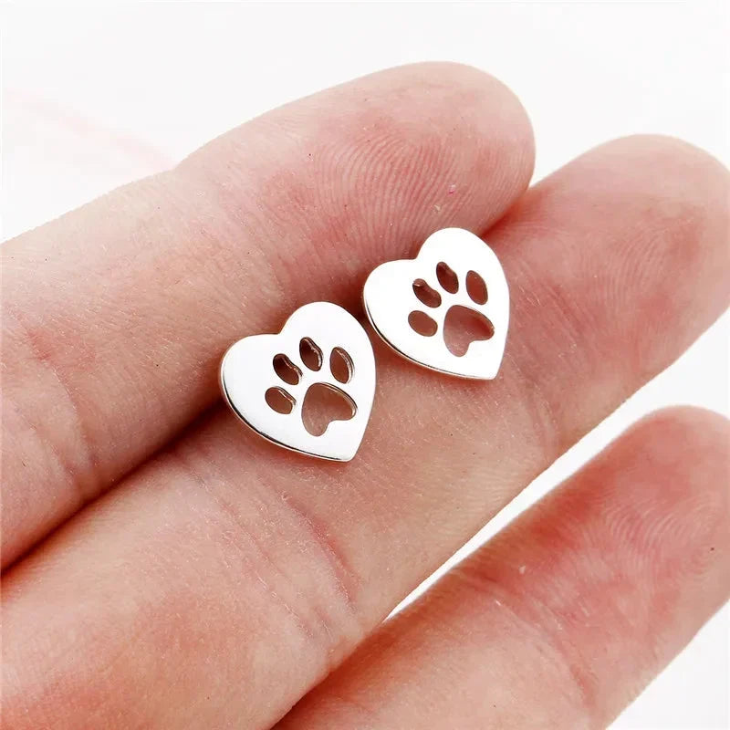 Silver heart stud earrings with paw cut-out held in the hand