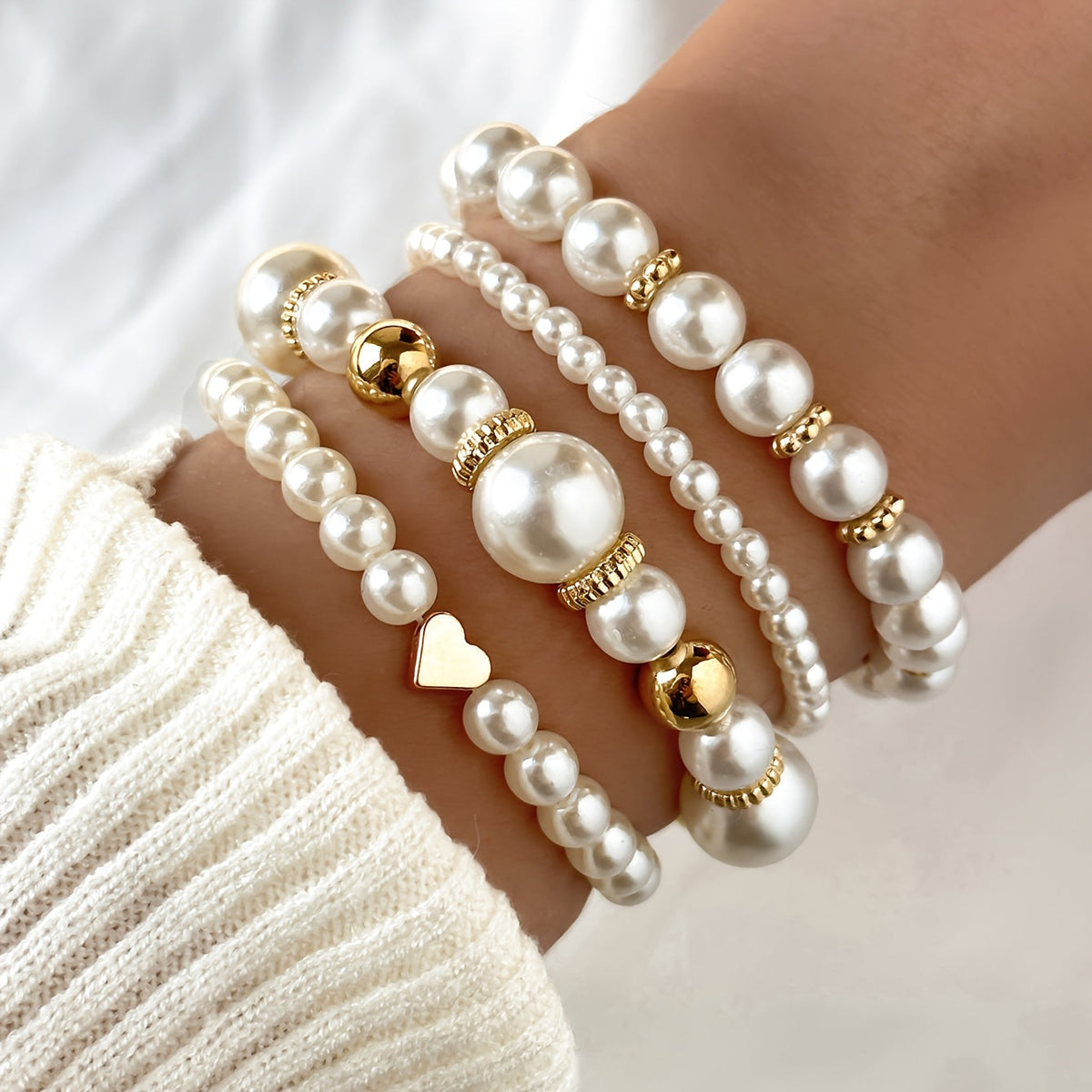 Pearl heart bracelet set in white with gold beads, stacked on wrist
