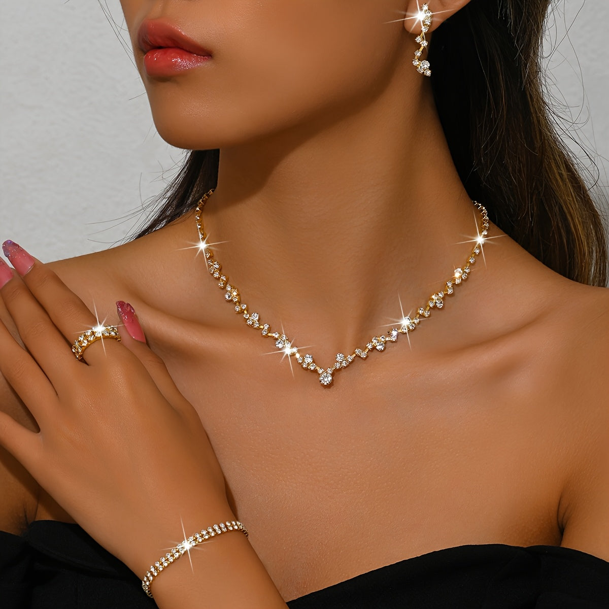 Gold crystal necklace with V-shaped centre worn with matching earring and bracelet
