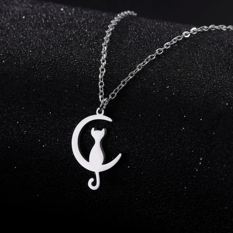Silver cat and crescent moon pendant necklace on dark background
