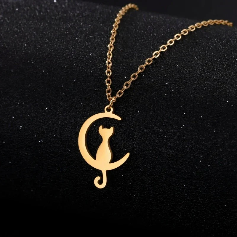 Gold cat and crescent moon pendant necklace on dark background