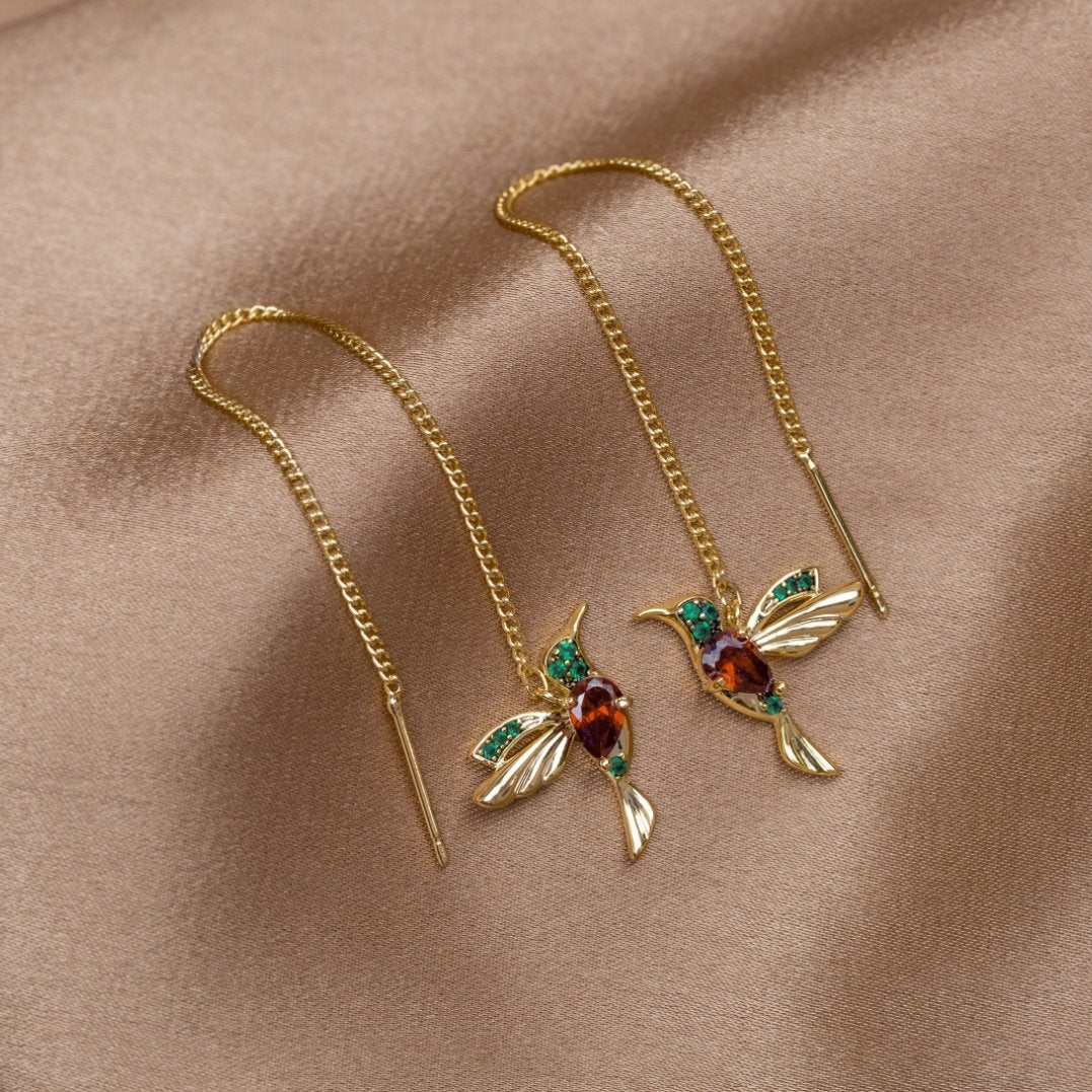 Stefanie gold hummingbird threader earrings on beige fabric