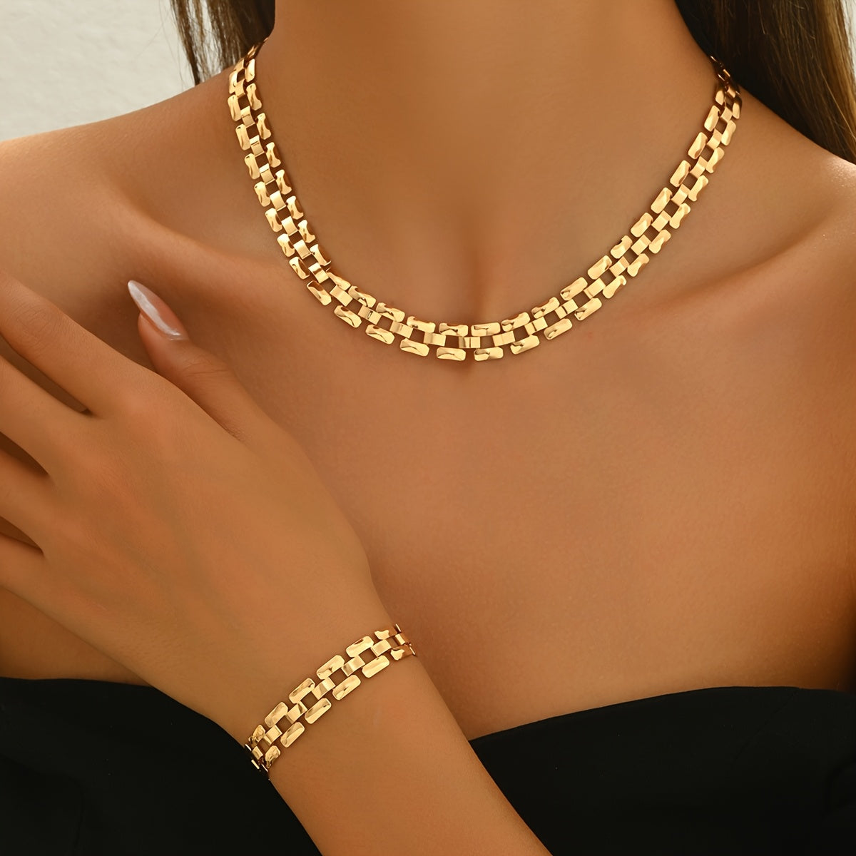 Gold polished link necklace and bracelet worn with black top