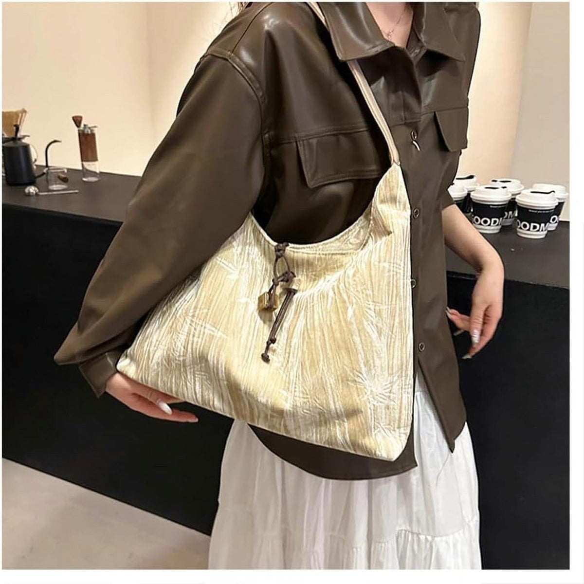 Amélie shoulder bag in champagne carried under the arm by a model