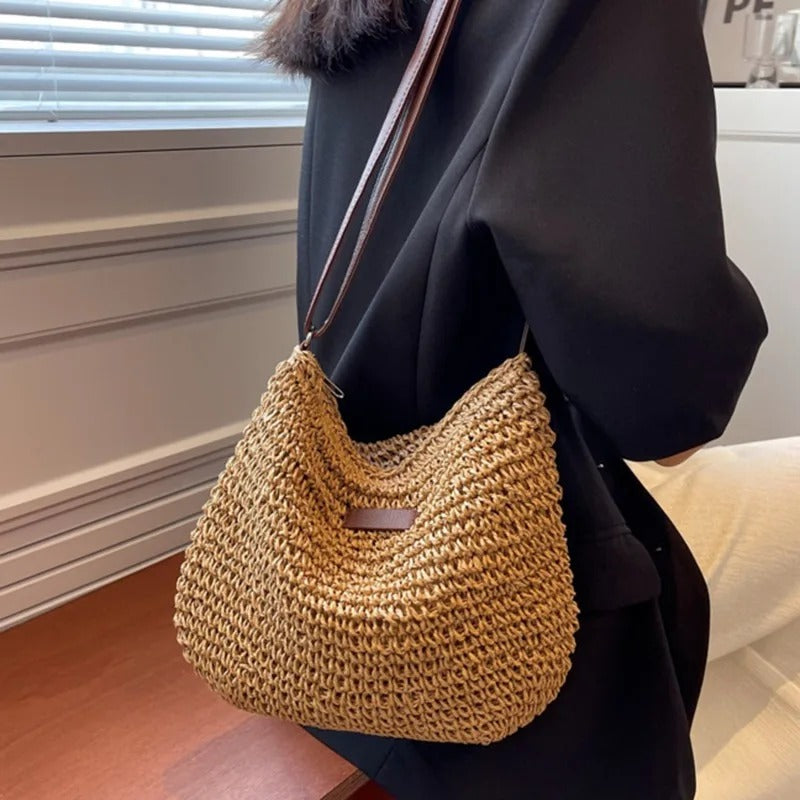 Woven shoulder bag in khaki worn over the shoulder with black tailoring