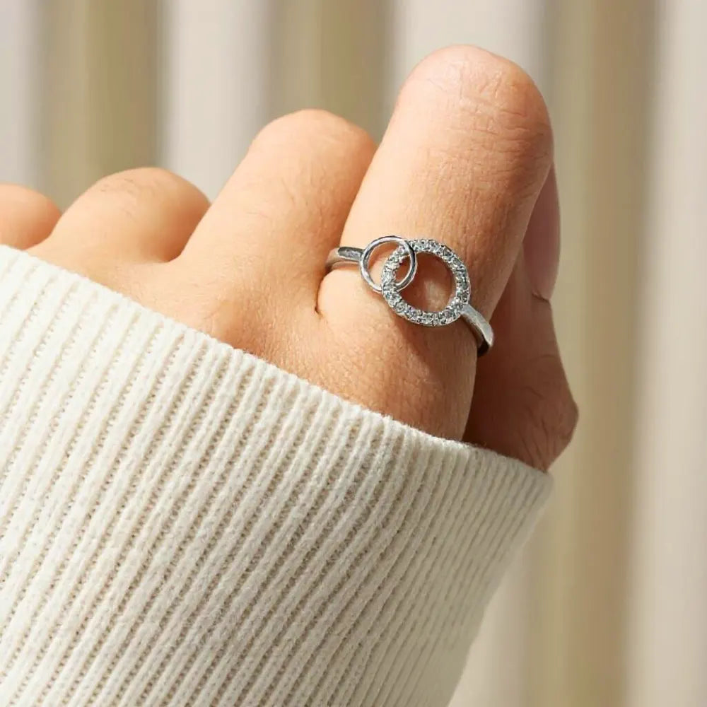 Silver sister ring worn on the finger with a cream knit sleeve