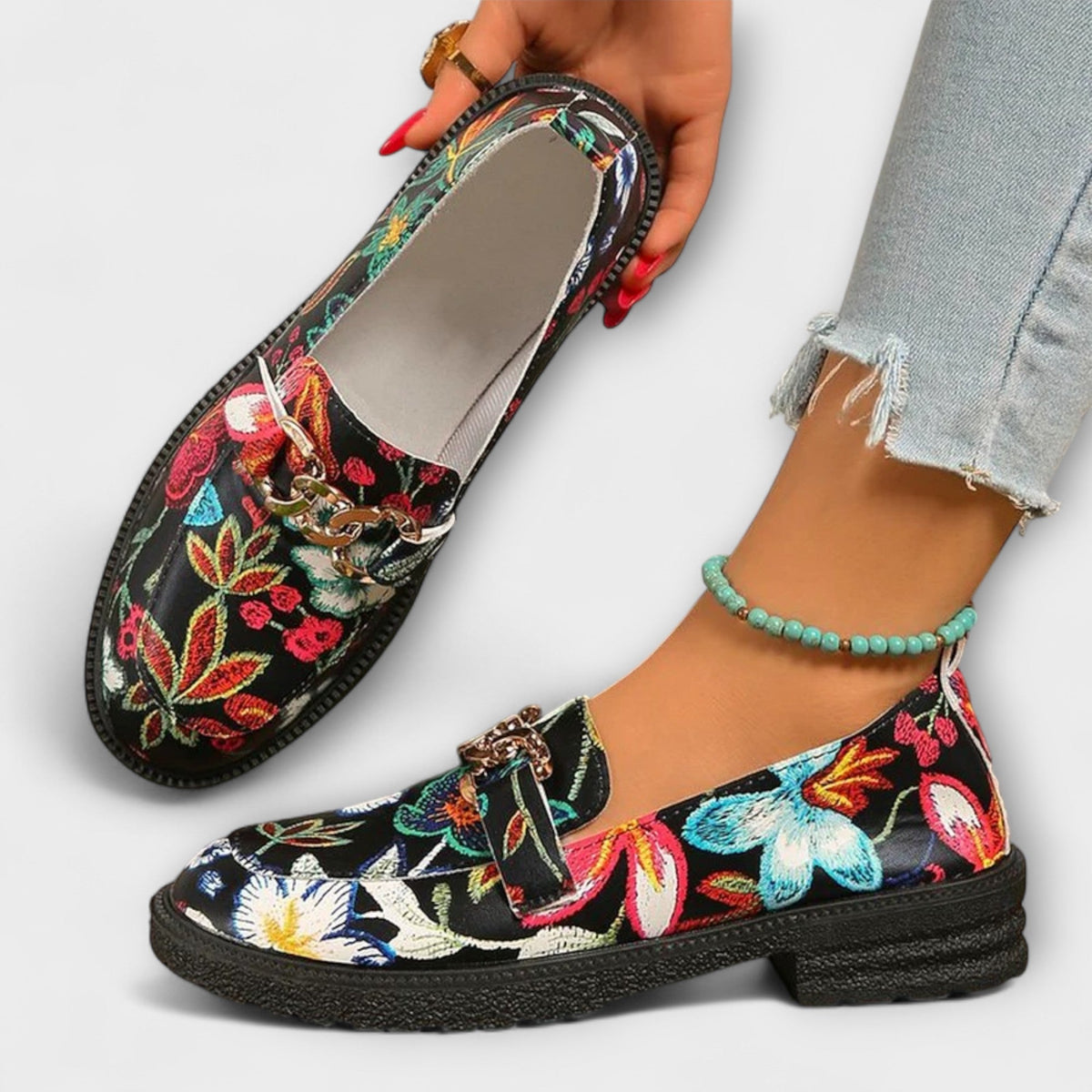 Camille loafer held in hand, showing pale lining and floral upper