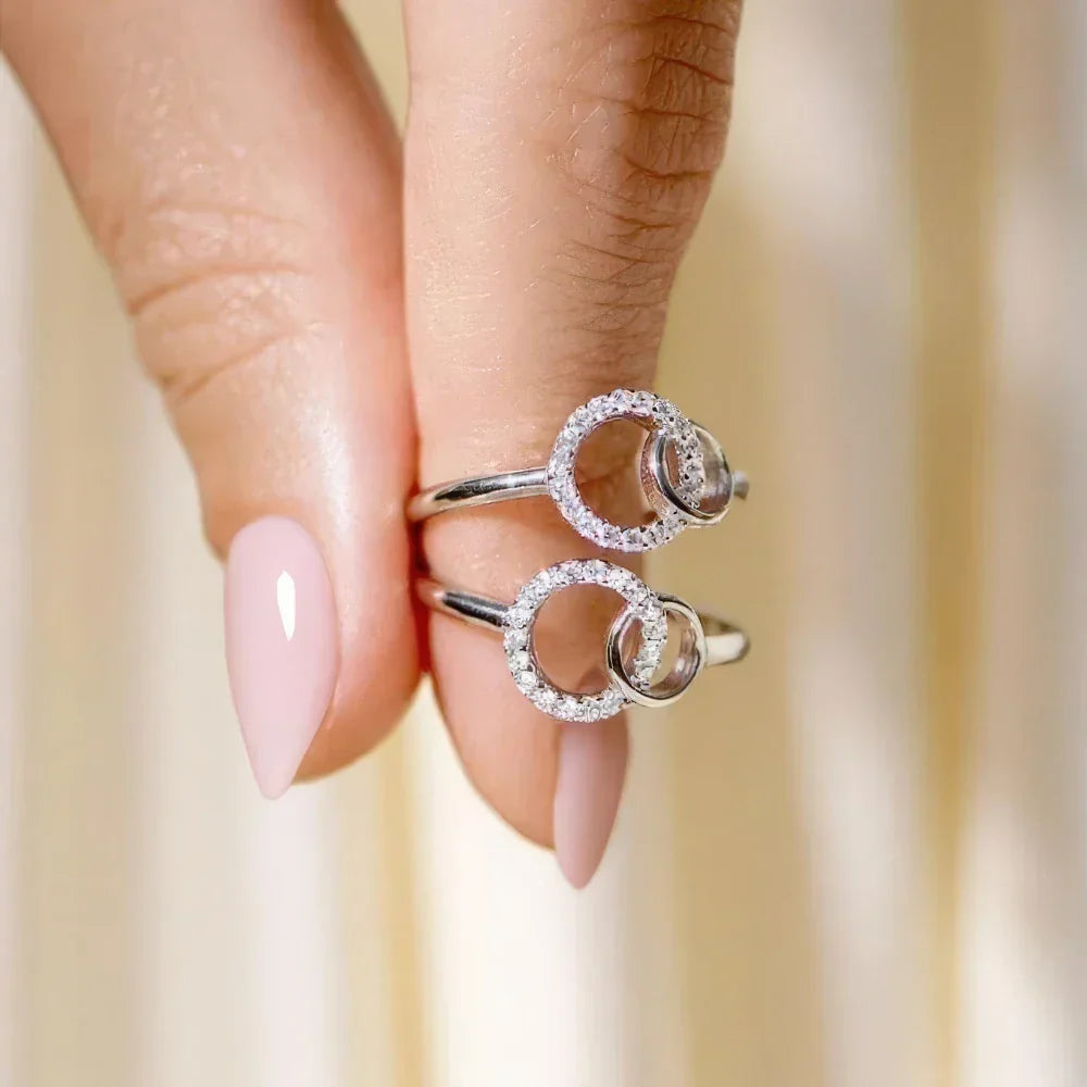 Two silver interlinked circle rings held between fingers, close-up view