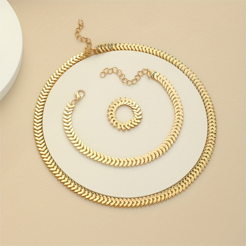 Gold necklace, bracelet and ring set laid flat on beige background