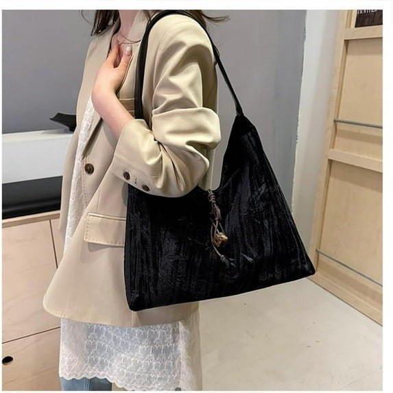 Amélie shoulder bag in black worn on the shoulder with a beige blazer