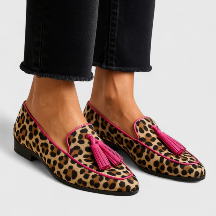 Elizabeth leopard print loafers with pink tassels, worn with black jeans, angled view