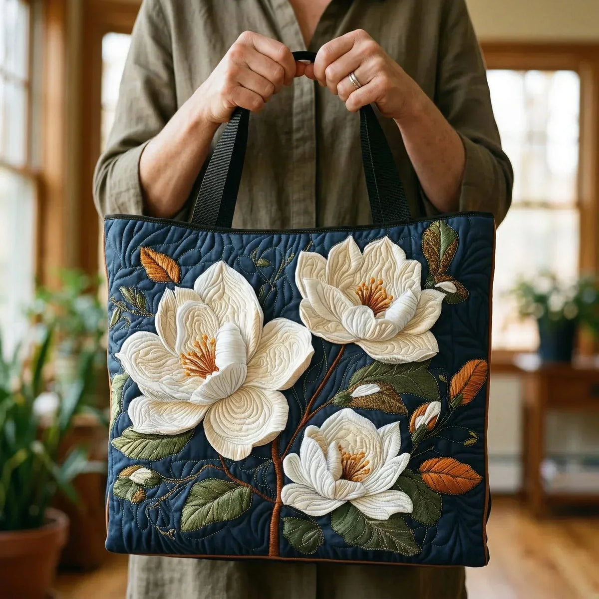 Navy magnolia tote bag held by the handles, front view indoors