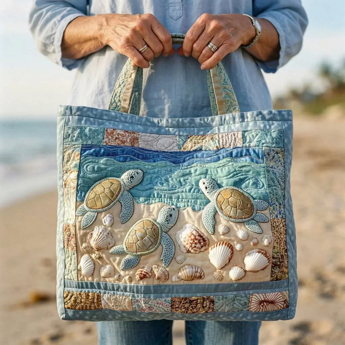 Woman holding the quilted sea turtle tote bag by its handles on the beach