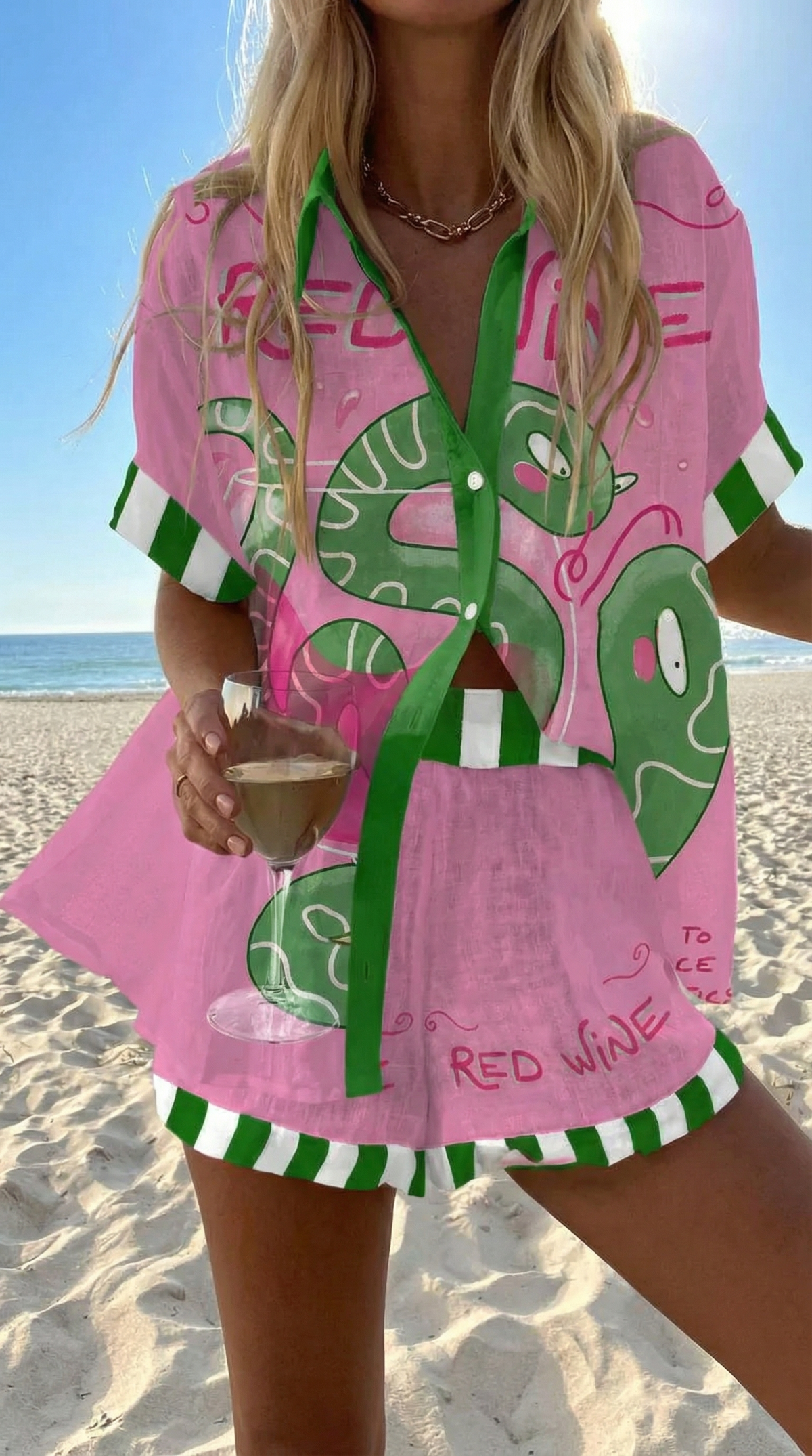 Rosa summer co-ord set in pink with green snake print, worn on the beach