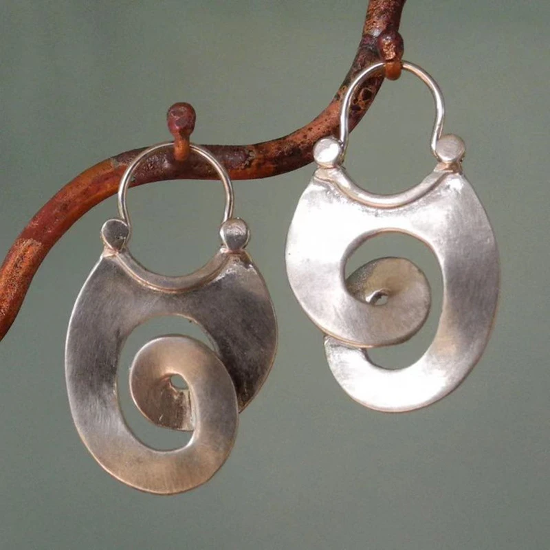 Irregular silver vintage spiral earrings with hook fastening, hanging from a branch