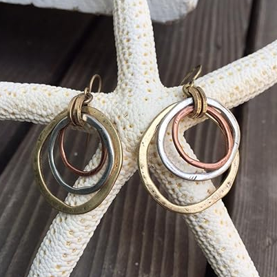 Two-tone drop earrings with layered gold, silver and copper rings, close-up view