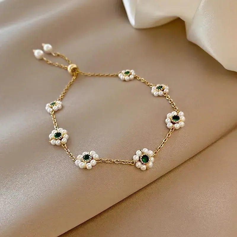 Daisy-inspired gold bracelet with pearl petals and green crystals on satin