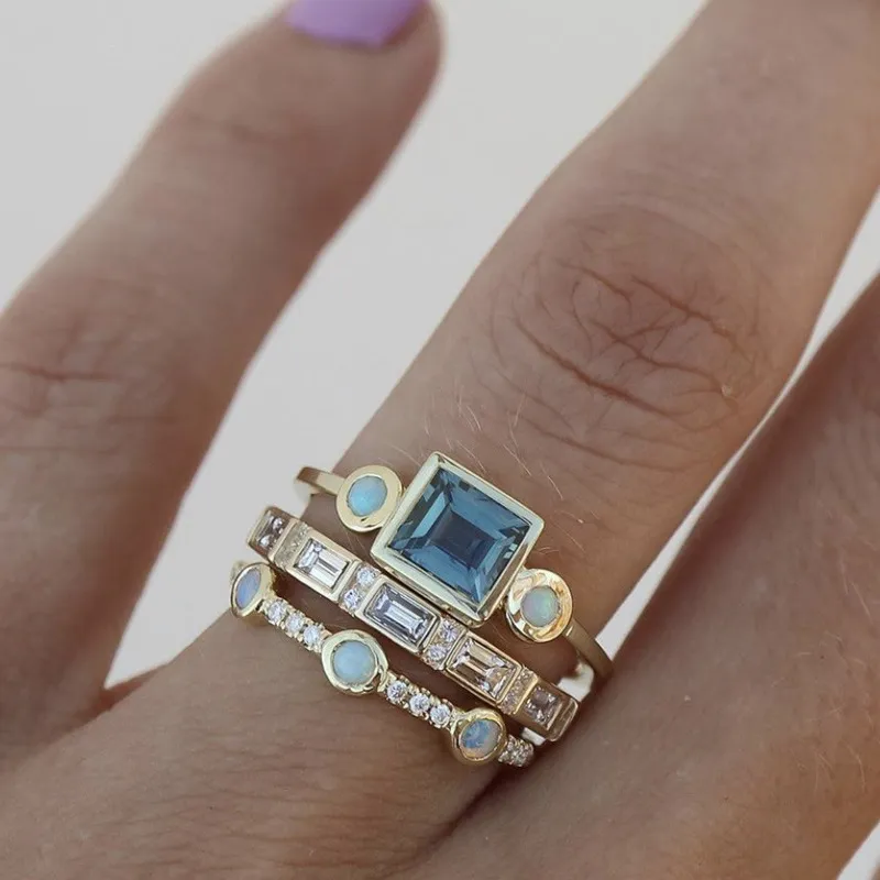 Blue crystal ring set worn stacked on a hand, close-up view