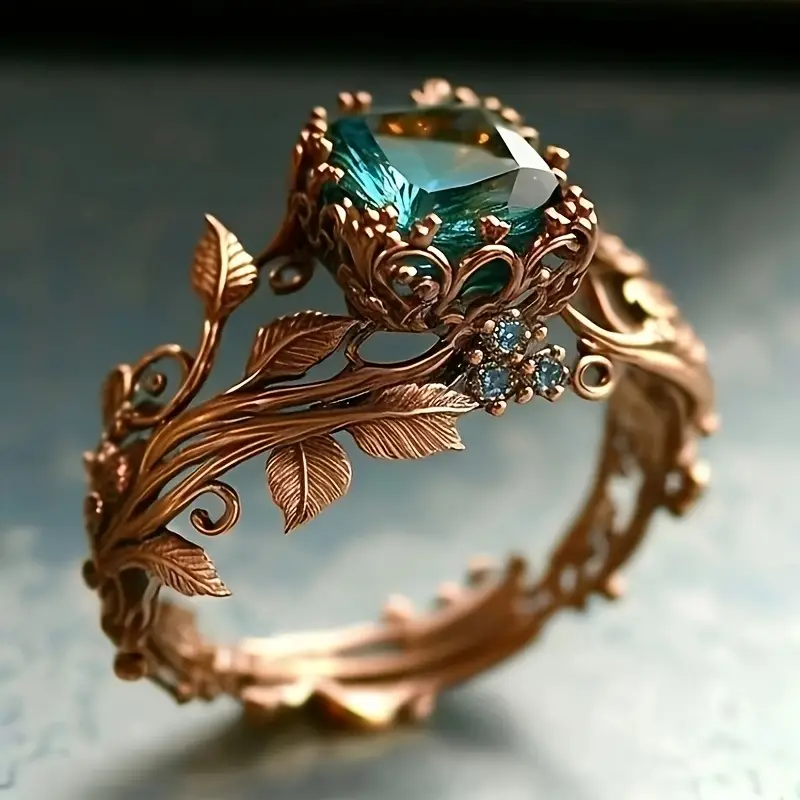Green crystal ring in gold tone with sculpted leaf band, angled view