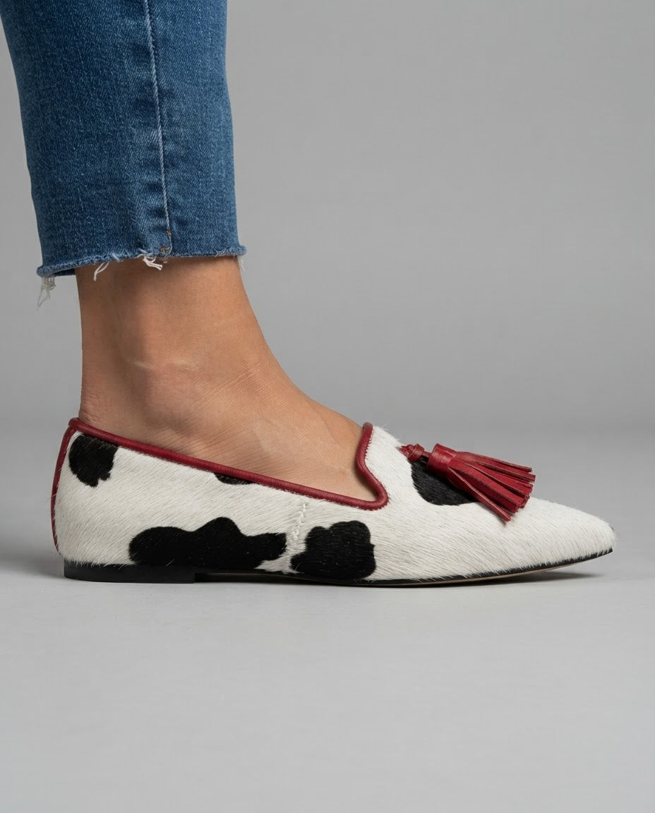 Ginevra cow print loafer side view showing red trim and flat heel