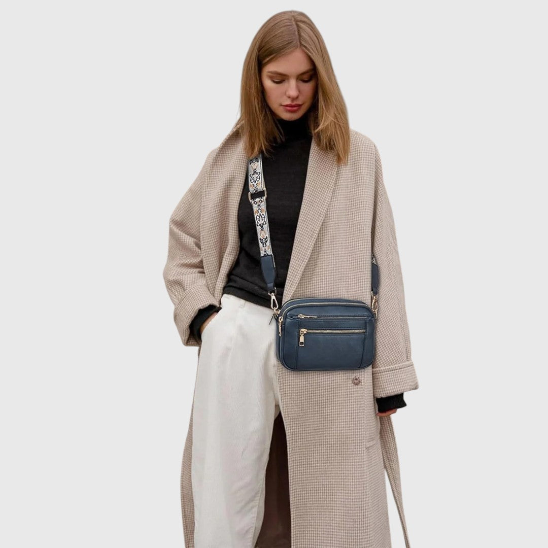 Dina shoulder bag in blue worn crossbody with a long coat