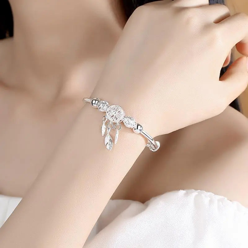 Silver dreamcatcher bracelet with feather charms worn on a model's wrist