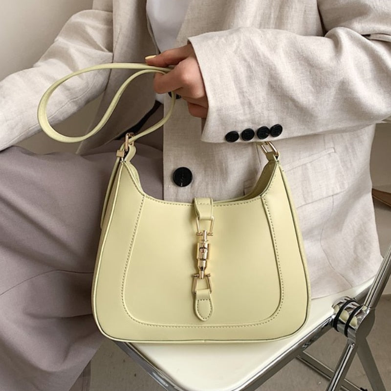 Classic curved shoulder bag in yellow held by the strap, seated view