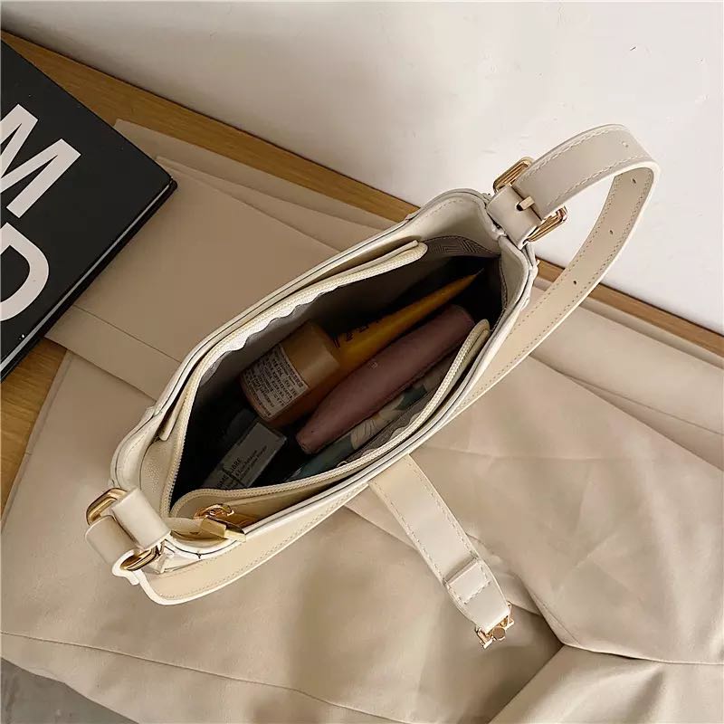Classic curved shoulder bag in white, open interior with everyday essentials