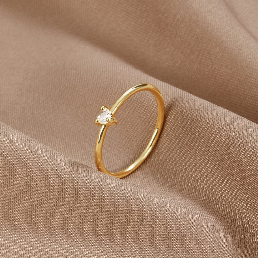 Leonie gold ring in gold resting on soft beige fabric, angled view