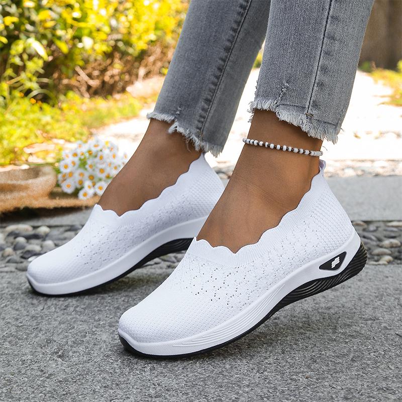 Ruth slip-on walking shoes in white, worn side view on a garden path