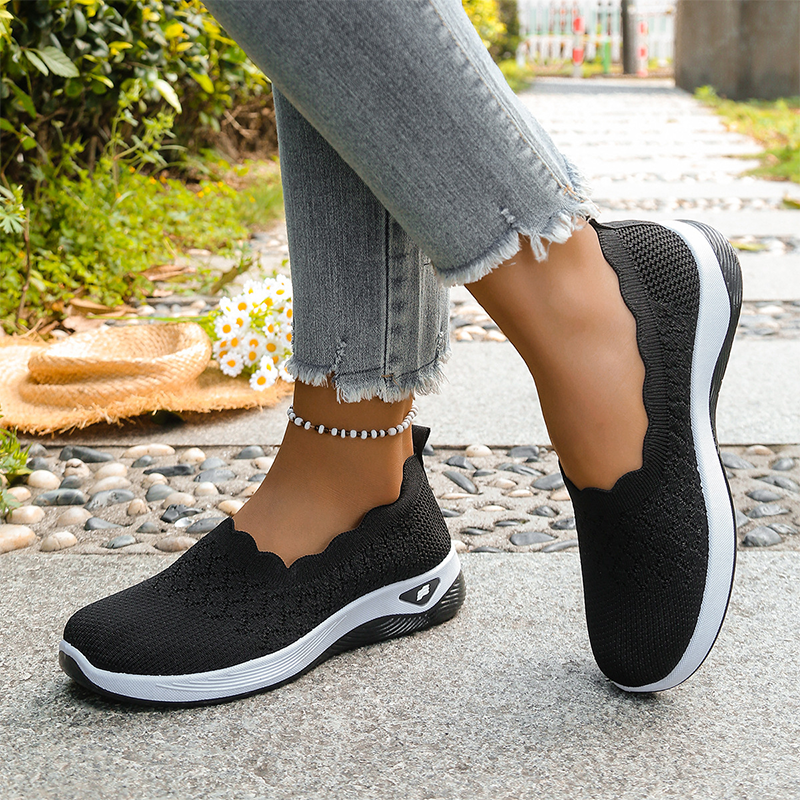 Ruth slip-on walking shoes in black, worn side view outdoors